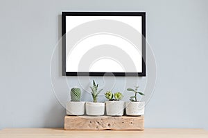 Minimalistic home interior with mock up photo frame on the brown table with composition of cacti and succulents.