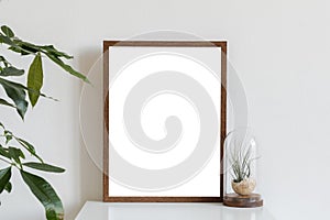 Minimalistic home interior with mock up photo frame on the brown table with composition of cacti and succulents.