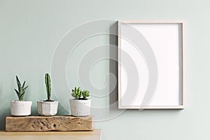 Minimalistic home interior with mock up photo frame on the brown table with composition of cacti and succulents.