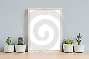 Minimalistic home interior with mock up photo frame on the brown table with composition of cacti and succulents.