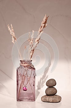 Minimalistic still life with a glass vase, decorative grass and a stone pyramid.