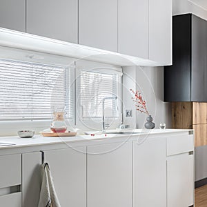 Minimalistic and modern white kitchen interior with furniture and kitchen accessories in stylish home decor. Windows. Details.