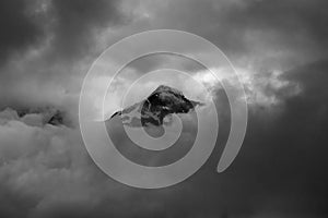 Minimalistic monochrome image of mountain peak shrouded in clou
