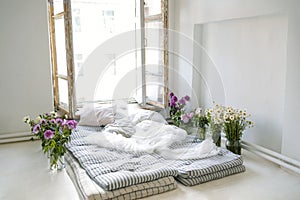 Minimalistic retro bedroom interior. Mattresses, pillows and a bedspread on the floor near the huge window