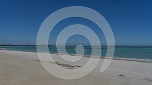 Minimalistic seascape. White sandy beach, calm endless turquoise ocean