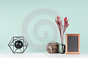 Minimalistic style of home workplace with black abstract atom model, red branch, blank photo frame, decorative sheaf of twigs.