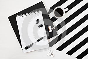 Minimalistic workspace book, notebook, pencil, cup of coffee, earphones on striped black and white background. Flat layTop view