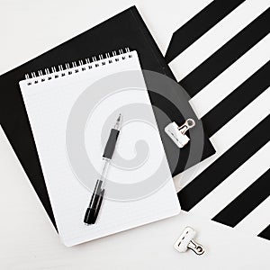 Minimalistic workspace with book, notebook, pencil on striped black and white background. Flat lay style Top view