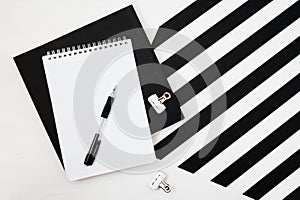 Minimalistic workspace with book, notebook, pencil on striped black and white background. Flat lay style Top view
