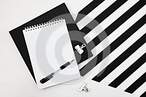 Minimalistic workspace with book, notebook, pencil on striped black and white background. Flat lay style Top view