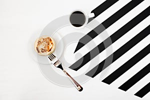 Minimalistic workspace with cup of coffee, bakery, isolated on striped black and white background. Flat lay style Top view.