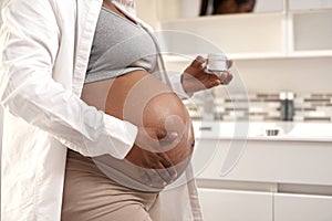 Minimise stretch marks with a good moisturiser. Closeup shot of a pregnant woman applying cream on her stomach at home.