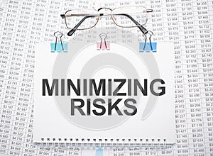 minimizing risks text written on paper with pen and glasses