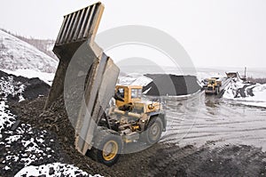 A mining dump truck unloads a mountainous land