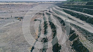 Mining dump trucks in large granite open pit mine. Empty truck rides on quarry ledge road