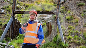 Mining engineer, a geologist in the protective reflective vest, gloves and helmet, with hammer in hand.