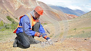 A mining engineer or geologist wearing gloves, a helmet, a reflective waistcoat