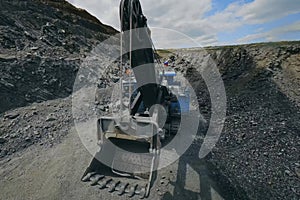 Mining excavator with bucket in industrial quarry. Crushed stone