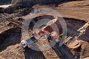 Mining excavator load the sand into dump truck in open pit. Developing the sand in the opencast. Heavy machinery on earthworks in