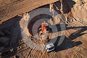 Mining excavator load the sand into dump truck in open pit. Developing the sand in the opencast. Heavy machinery on earthworks in