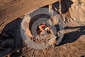 Mining excavator load the sand into dump truck in open pit. Developing the sand in the opencast. Heavy machinery on earthworks in