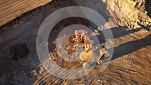 Mining excavator load the sand into dump truck in open pit. Developing the sand in the opencast. Heavy machinery on earthworks in