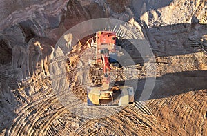 Mining excavator load the sand into dump truck in open pit. Developing the sand in the opencast. Heavy machinery on earthworks in