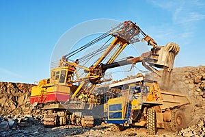 Mining. excavator loading granite or ore into dump truck