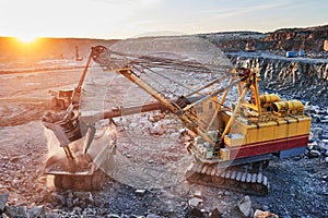 Mining. excavator loading granite or ore into dump truck