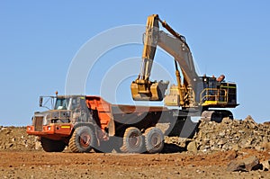 Mining Excavator loading truck in mine quarry