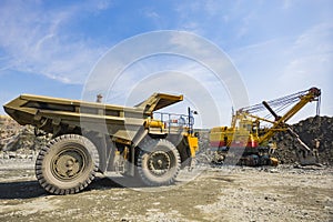 A mining excavator loads a heavy truck with granite rock huge machines