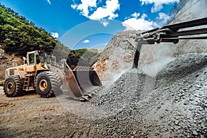 Mining industry - Heavy duty wheel loader bulldozer loading granite rock or ore at crushing