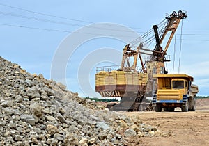 Mining truck and excavators working in the limestone open-pit. Loading and transportation of minerals in the dolomite mining