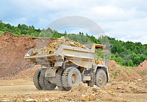 Mining truck and excavators working in the limestone open-pit. Loading and transportation of minerals in the dolomite mining