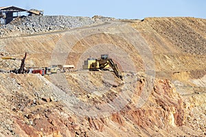 Mining trucks and machinery in Corta Atalaya open mine pit. Deep excavation of pyrite and extraction of minerals of cooper and