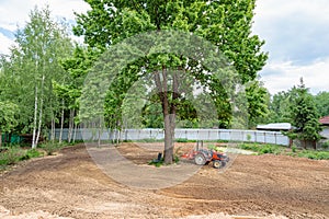 Minitractor on a cultivated plot of land next to a tree