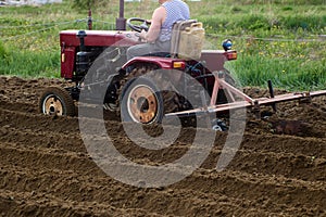 Minitractor with suspended plow cultivates soil in an agricultural field.