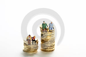 miniture figure retired couple sat on a stack of pound coins