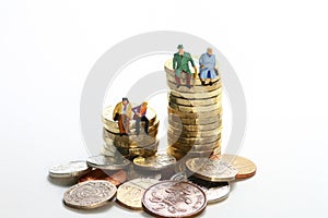 Miniture figure retired couple sat on a stack of pound coins