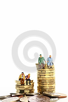 Miniture figure retired couple sat on a stack of pound coins