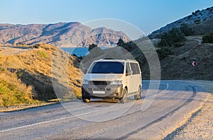 minivan moves along road off mountainous sea coast