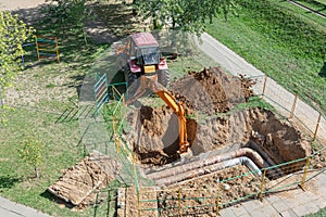 Minsk, Belarus - 09/12/2018: Tractor digs a pit to repair a burst heating pipe