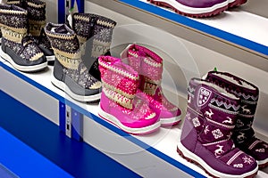 MINSK, BELARUS - MARCH 22, 2021: Colorful waterproof winter kid boots on retail shoes shop display shelf.