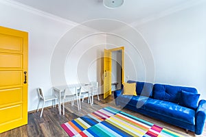 MINSK, BELARUS - March, 2019: retro bright interior of hipster flat apartments with blue sofa, yellow door and colored carpet