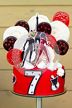 Minsk, Belarus, 08.08.2020: Red cake with Lady Bug and Supercat for child`s birthday with number 7, isolated on white