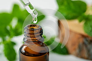 Mint essential oil drop falling from dropper into the bottle photo