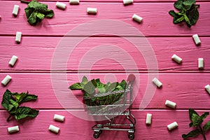 Mint gum, mint and small cart on pink wooden background 2