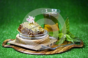 Mint herbal tea in armud and honey in comb on green background