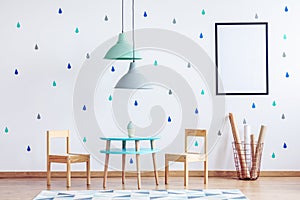 Mint and pastel blue lamps above small table and wooden chairs for kids