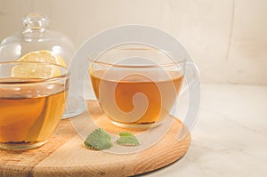 Mint tea in glass with lemon/two tea with galss, lemon and leaves of mint on a wooden tray. Selective focus